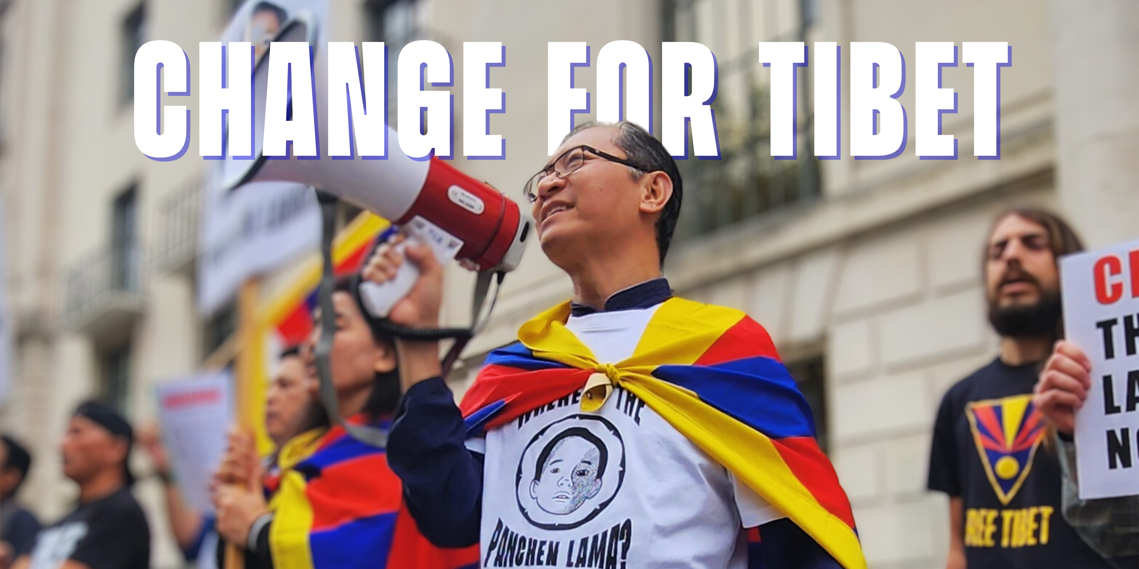 Tenzin Kunga from Free Tibet protesting outside the Chinese embassy in London, holding a megaphone and wearing a t-shirt that says "Where is the Panchen Lama?"