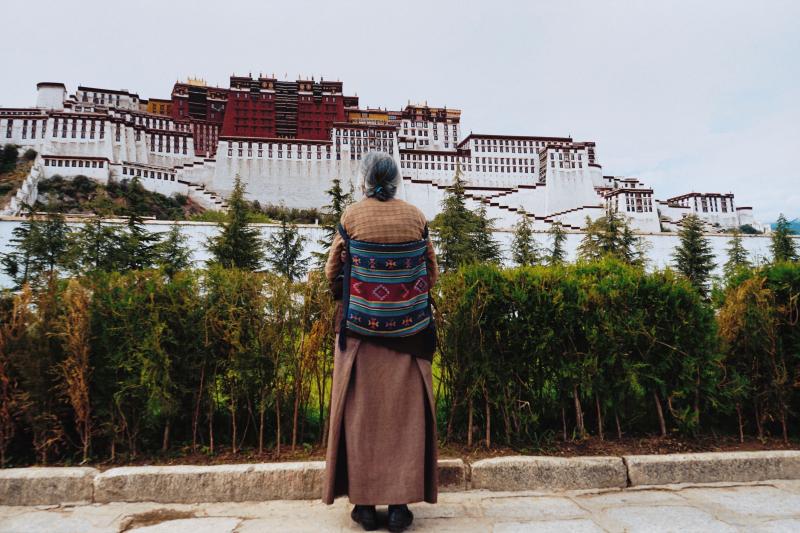 Tibetan woman looks out to the Potala Palace.